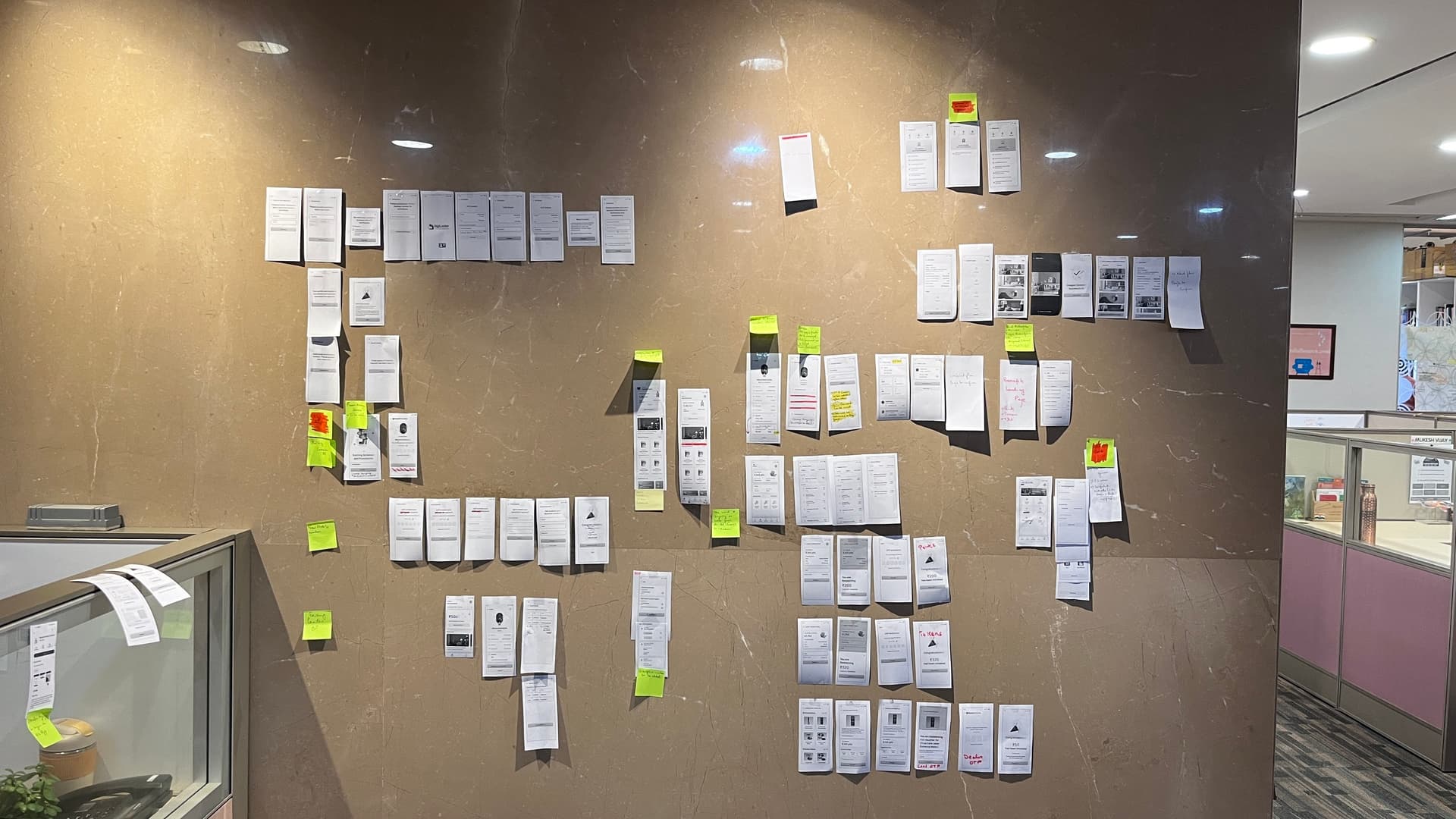 Wall-mapping the cross-brand app — every existing screen printed and taped up, sticky notes calling out gaps and duplications. Standing in front of the whole thing at once is what made the unified header surface as the wedge.
